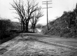 Dirt Road With Steep Bank and Farm in Distance