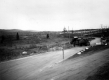 Dirt Road with Trucks and Cemetery in Background