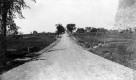 Gravel Road Bordered By Wire Fence and Electrical Wires
