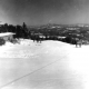 Skiers on a Groomed Slope with Mountains in the Distance