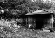 Three men eating outside wood and metal hut