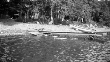 Dock, boat and house along the shore of a lake