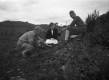 Three people examining a rock outcrop