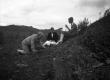 Three people examining a shale outcrop