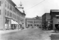 Downtown area with automobiles and horse drawn wagons