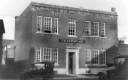 Telephone building with two automobiles in front