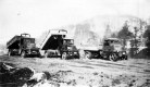 Three dump trucks in a clearing