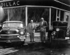 Two men in front of a Cadillac Dealer