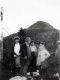 Group of People Posing on Rock in Front of Mountain