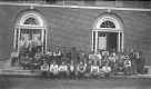 Group of Men Posing in Front of Brick Building