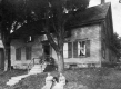 Two Women sitting on a Grass lawn in front of a house