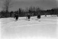 Three Men Skiing Down a Small hill