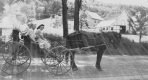 A man and two women in a carriage with a boy on the back