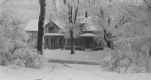 Snow covered house surrounded by trees