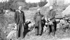 Three men standing by a stone wall