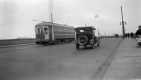 Trolley Car and Automobile Driving Along Paved Roads