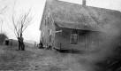 Two Figures Stand Outside a Dwelling