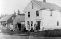 Figures Stand in front of House