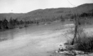A body of water with a hill in the background