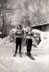 Two Women Skiers Pose in front of Firewood
