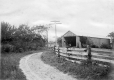 Dirt road leading to a wooden-frame building