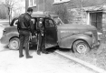 Uniformed men looking in a car