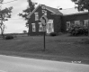 House Covered in Ivy Next to Road and Road Sign