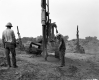 Two Men Work with Machinery at Construction Site