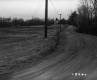 Unpaved Road with Utility Lines and White Dwelling