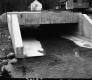 Concrete Culvert over Downs Brook in Middlesex, up-close view with Dwellings in The Background