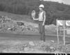 Sandy Wood, Flag Person at Construction Site in Barnet, Piles of Rubble and Debris in the Background
