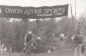 A bike racer rides under a banner