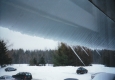 A parking lot and a snow sheet sliding off a roof