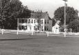 White colonial house with runners passing by