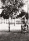 A man pushing a jogger along a tree-lined fence