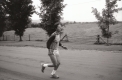 A woman running on a dirt road with a field in the background