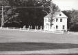 Eight people run along the Craftsbury Common past a white house
