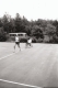 A seated man filming a runner with a bus in the background
