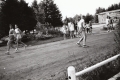 A group of runners gathered on a dirt road with a building in the background