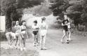 A group of eight runners stand in a dirt road
