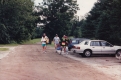 Five people walk up a dirt road carrying bags