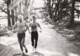 A man and woman run along a sunny dirt road